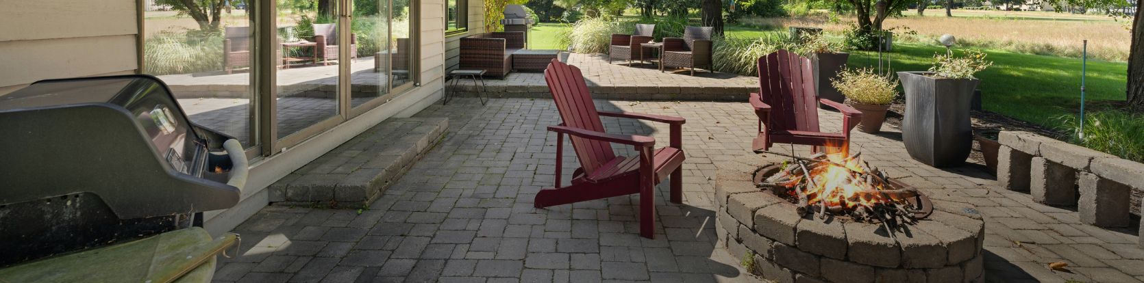 firepit in the backyard next to a grill and patio chairs